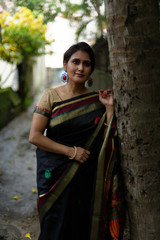 Portrait of a beautiful brunette Indian bengali thoughtful woman in traditional wear sari standing...
