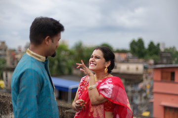 A brunette Indian Bengali romantic couple in traditional wear interacting between themselves on a...