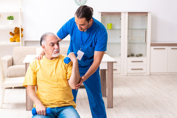 Fototapeta premium Young male doctor visiting old patient at home