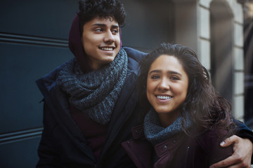 Portrait of a happy young hispanic couple smiling and holding each other while walking ouitside on a sunny day