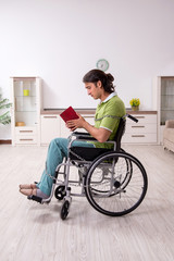Young male invalid in wheel-chair suffering at home