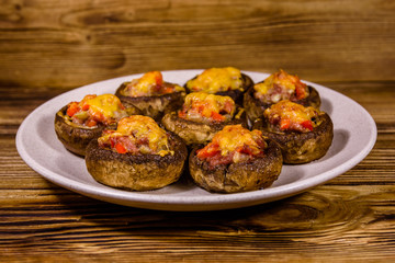 Baked champignons stuffed with minced meat and cheese in plate on a wooden table