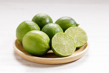 Naklejka na ściany i meble Fresh green limes and half on white wooden background