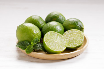 Fresh green limes and half on white wooden background