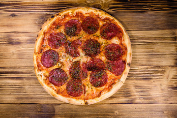 Pizza with salami sausage and parmesan cheese on a wooden table. Top view