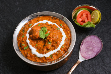 Butter chicken, Murgh Makhani curry  hot and spicy gravy dish on dark black background in Punjab, Hyderabad Kashmir North India. Top view of popular Indian curries non veg food. 