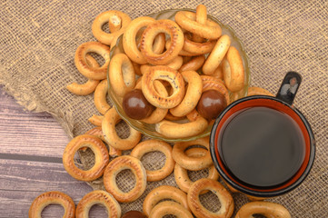 Small bagels, chocolates, a mug of tea and a rough homespun cloth on a wooden background close-up.