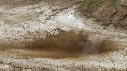 Fast Buggy car floating in muddy puddle dirt splash on off road track, side front view