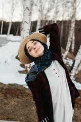 Fototapeta na wymiar portrait of young European Muslim women with hijab standing in forest in nature. Snow and trees are in the background. She is holding a hat. 