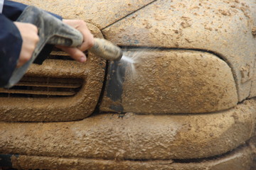 Muddy headlight car 4x4 American power truck close up high pressure cleaning