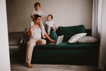 Children around dad working on laptop at home