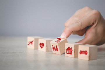 Hand arranging wood block stacking with icon insurance: car,