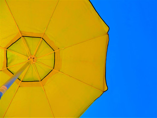 Yellow beach umbrella, blue sky in the background