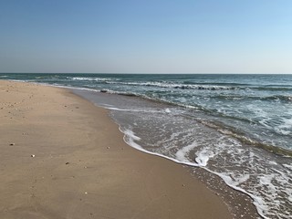 Sea waves blow onto the sandy beach on the coast