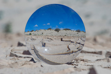 eine Glaskugel zeigt ausgetrocknete, aufgerissene Landschaft im Klimawandel,  Bodenerosion,...