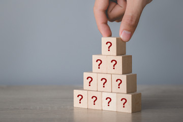 Hand arranging wood block stacking with icon question mark,thinking with question mark concept.