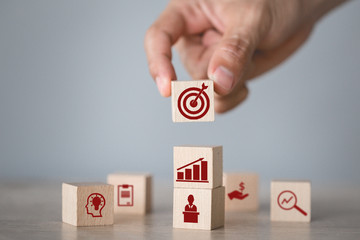 Hand arranging wood block stacking with icon arrow and business,targeting the business concept.