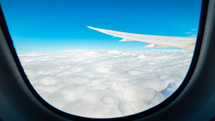 Fototapeta na wymiar Window view of airplane wing fly over the blue sky and white cloud