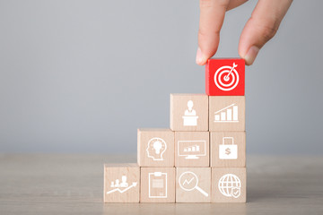 Hand arranging wood block stacking with icon arrow and business,targeting the business concept.