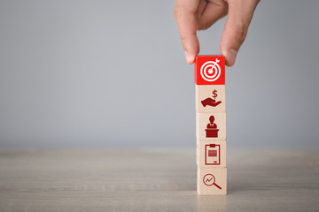 Hand arranging wood block stacking with icon arrow and business,targeting the business concept.