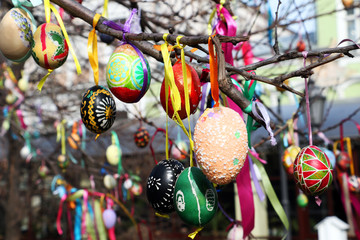 Easter eggs on a tree. Multicolored decorated eggs hanging on satin ribbons.Handmade decoration.