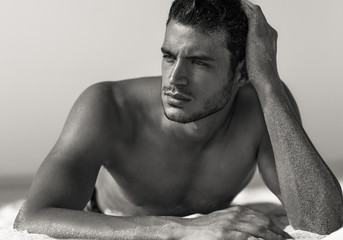 Sexy Porträt eines hübschen topless männlichen Modells am Strand. Schwarz und weiß.