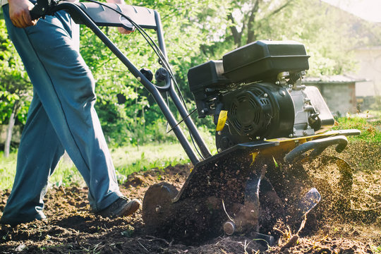 A man during soil plow process by motor cultivator