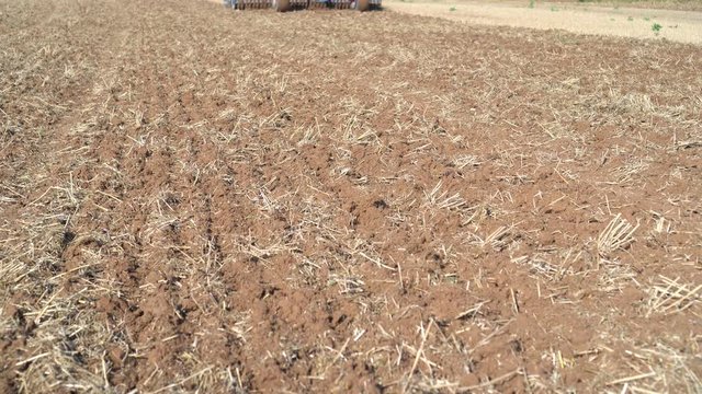 Agriculture machine tractor discing stubble field. cultivating farm land soil.