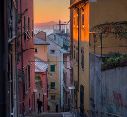Beautiful scenic view of Genoa's (Genova) symbol of the city: Lanterna (lighthouse) view from the characteristic typical colorful narrow alleys (caruggi or vicoli) and colored houses of this old town - obrazy, fototapety, plakaty