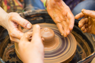 A close up view on ceramic production process on potter's wheel with children. Clay crafts with kids concept.