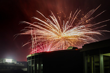 Helles Feuerwerk in der Nacht &uuml;ber einem Dach.