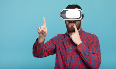 Young man using VR glasses headset trying to touch objects in virtual reality. Isolated white background.