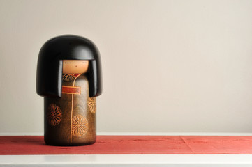 Japanese Kokeshi doll on red obi with white background