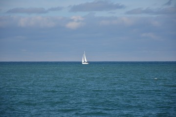 white sailboat in the sea on the horizon