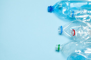Crumpled plastic bottles on a blue background. Plastic trash. Copy space for text.