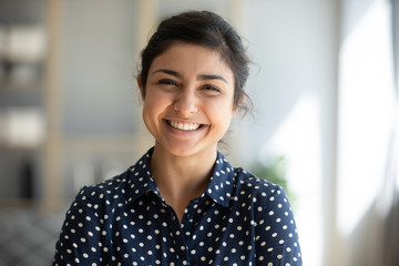Cheerful indian girl standing at home office looking at camera - obrazy, fototapety, plakaty