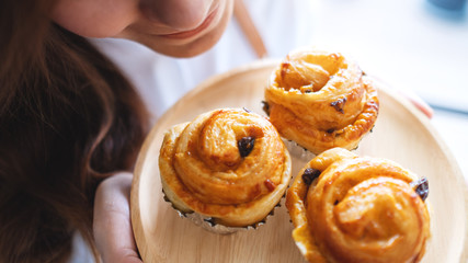 A waitress holding and smelling raisin danish in wooden plate