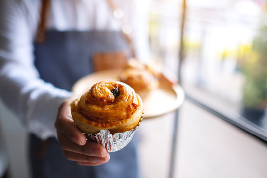 A waitress holding and giving a piece of raisin danish