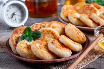 Cottage cheese pancakes, syrniki with honey on a plate on wooden background