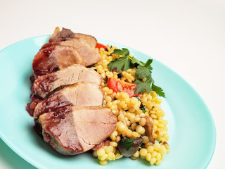 Duck breast fillet with garnish and sauce on a plate on a white background.
