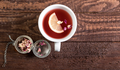 Cup of rose tea on dark wooden background. Top view with copy space.