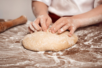 Obraz premium Hands of the child knead dough on a table. Soft focus.