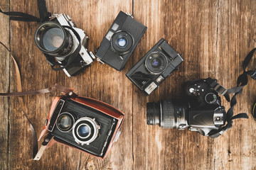 The evolution of the photo cameras on a wooden backraound. Camera technology concept.