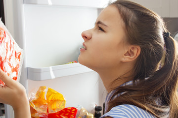 The girl looks in the refrigerator because of an unpleasant smell, thinks that it is rotten