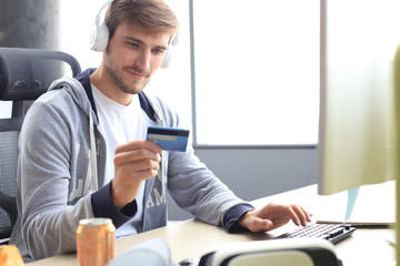 Portrait of a young man holds and using credit card for game money top up.