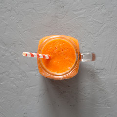 Homemade Mango Carrot Smoothie in a glass jar mug over gray background, top view. Flat lay, overhead, from above. Close-up.