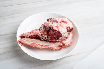 A plate of fresh beef bones on a kitchen tile countertop