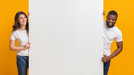 Big White Advertisement Board In Hands Of Happy Interracial Couple
