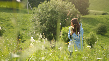 Pretty woman walks with flowers in the field