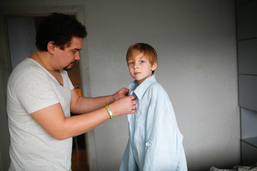 Obraz premium Like Dad. Dad fastens his big shirt to his son